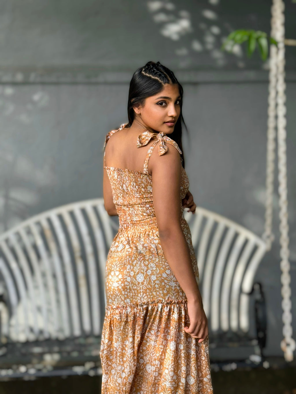 Woman in Hoya Tie-Straps Sun Dress standing in front of a swing and bench.